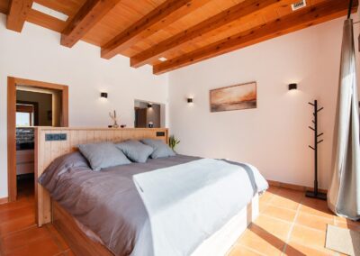 Dormitorio con cama de matrimonio y techo con vigas.