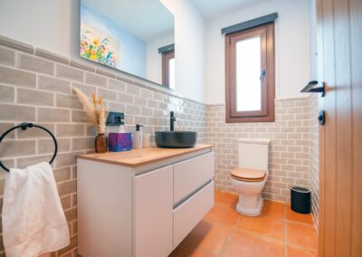 Cuarto de baño moderno con un lavabo negro, mueble suspendido y suelo de terracot