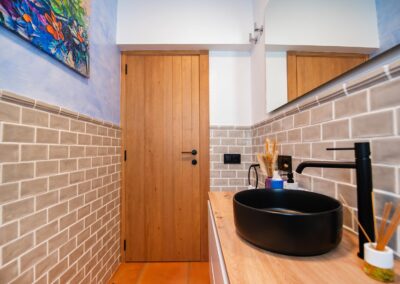 Cuarto de baño con un lavabo negro, inodoro y paredes de azulejos beige