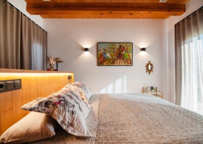 Primer plano de una cama con un cabecero de madera iluminado y un cuadro en la pared