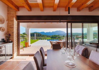 Comedor interior con vistas a una terraza, una piscina y un paisaje de la Sierra