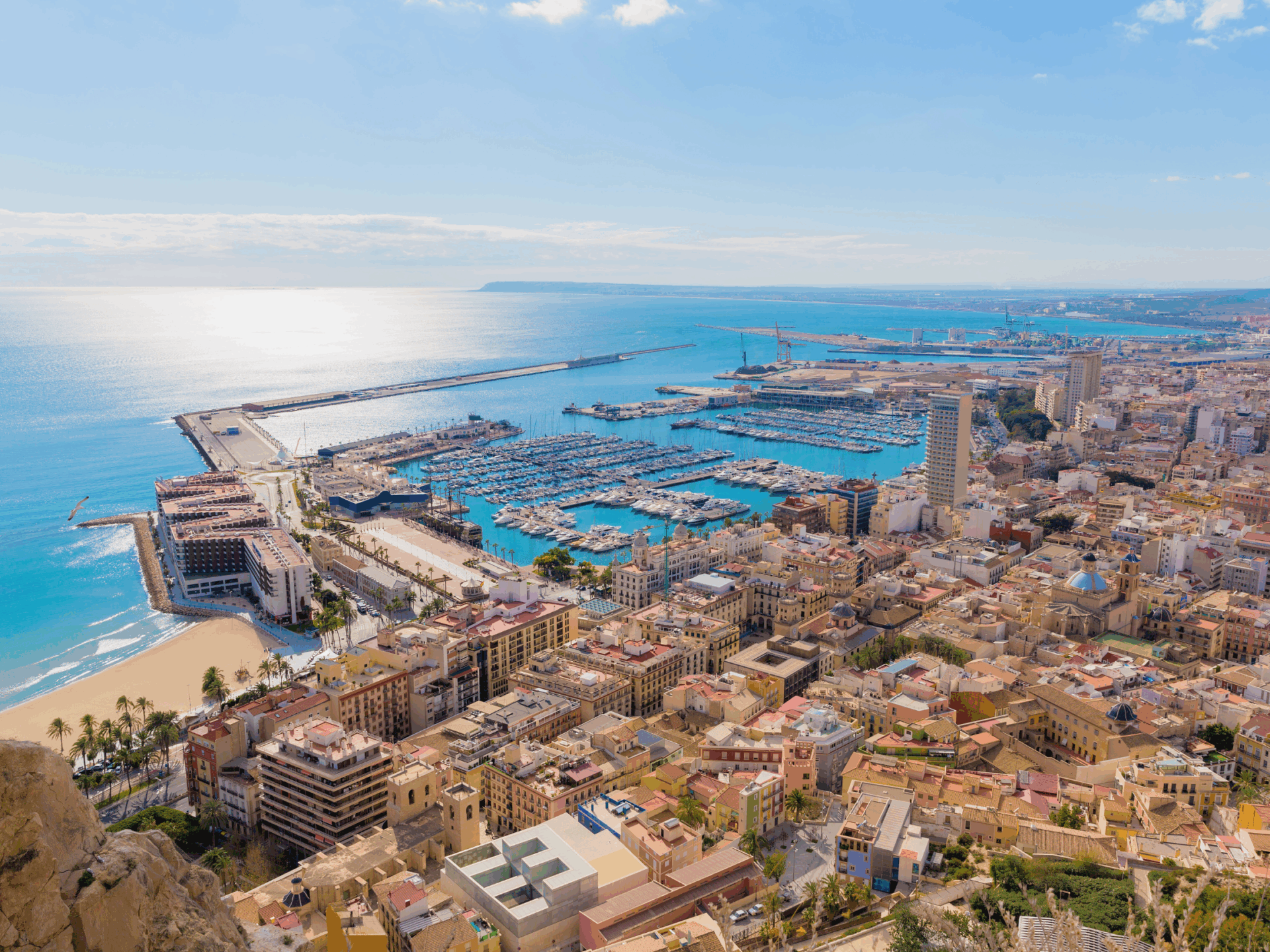 3 Vista panorámica de la ciudad de Alicante y su puerto deportivo bajo un cielo azul invernal, destacando la luz y las oportunidades de qué hacer en Alicante en otoño e invierno.