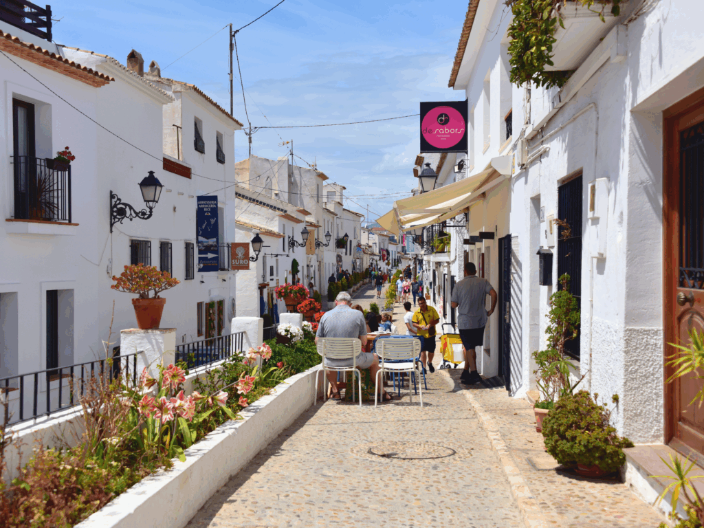 Calle empedrada y encalada del casco antiguo de Altea, con sus tradicionales casas blancas y balcones con flores, un ejemplo del encanto de los pueblos para una escapada rural en Alicante durante el invierno en Costa Blanca
